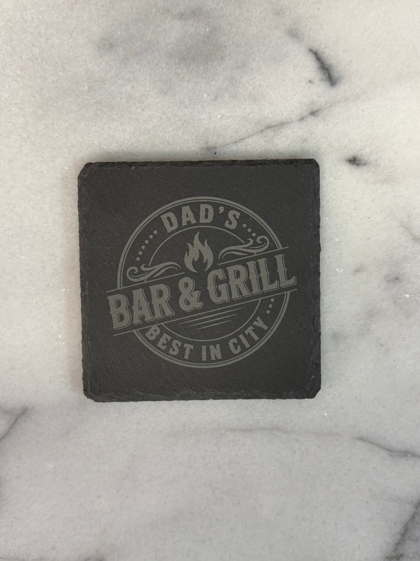 Close-up of hand-chiseled natural slate coaster with engraved business logo