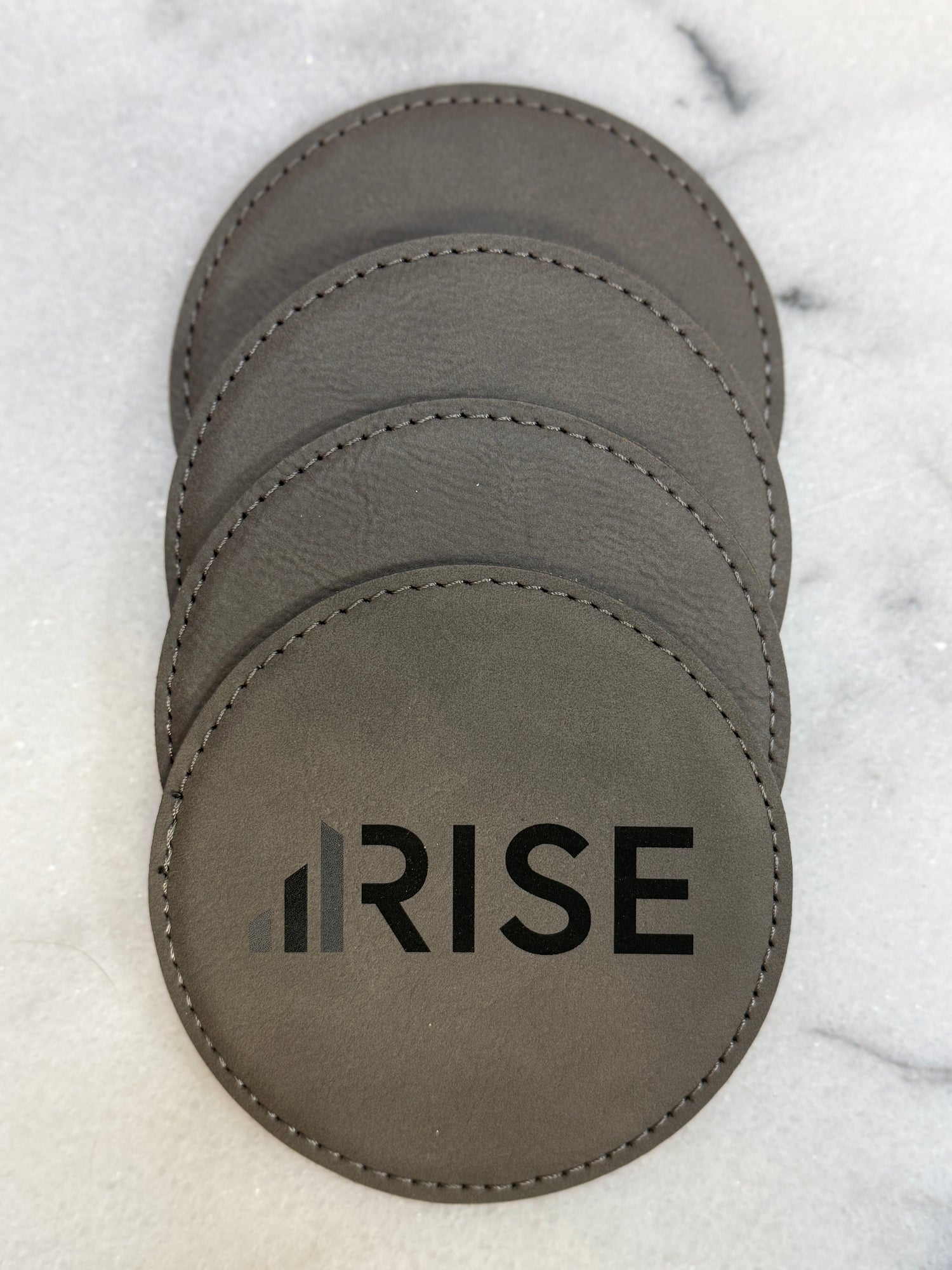 Custom engraved leatherette coasters with company logo for corporate gifting.
