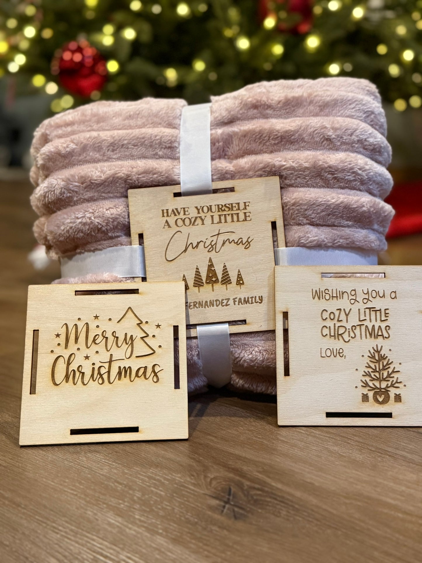 Custom wooden blanket gift tag secured to a blanket with ribbon