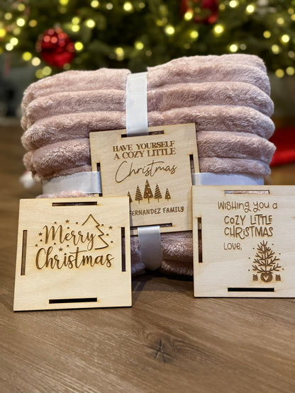 Custom wooden blanket gift tag secured to a blanket with ribbon