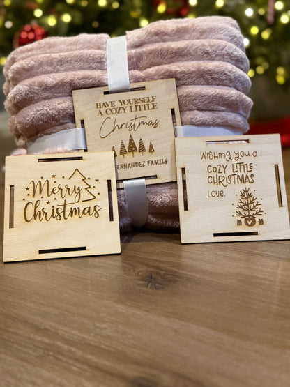 Custom wooden blanket gift tag secured to a blanket with ribbon