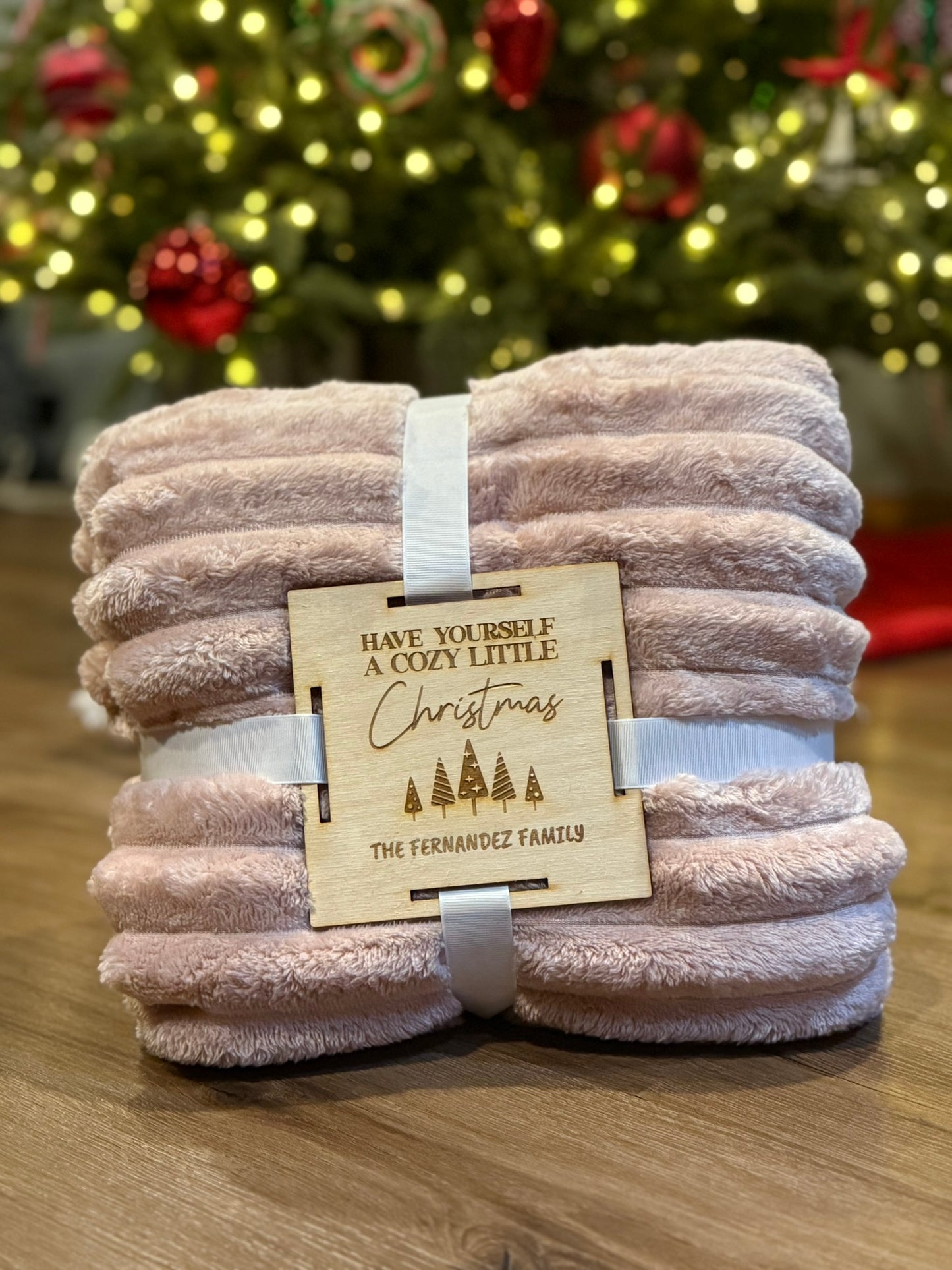 Custom wooden blanket gift tag secured to a blanket with ribbon