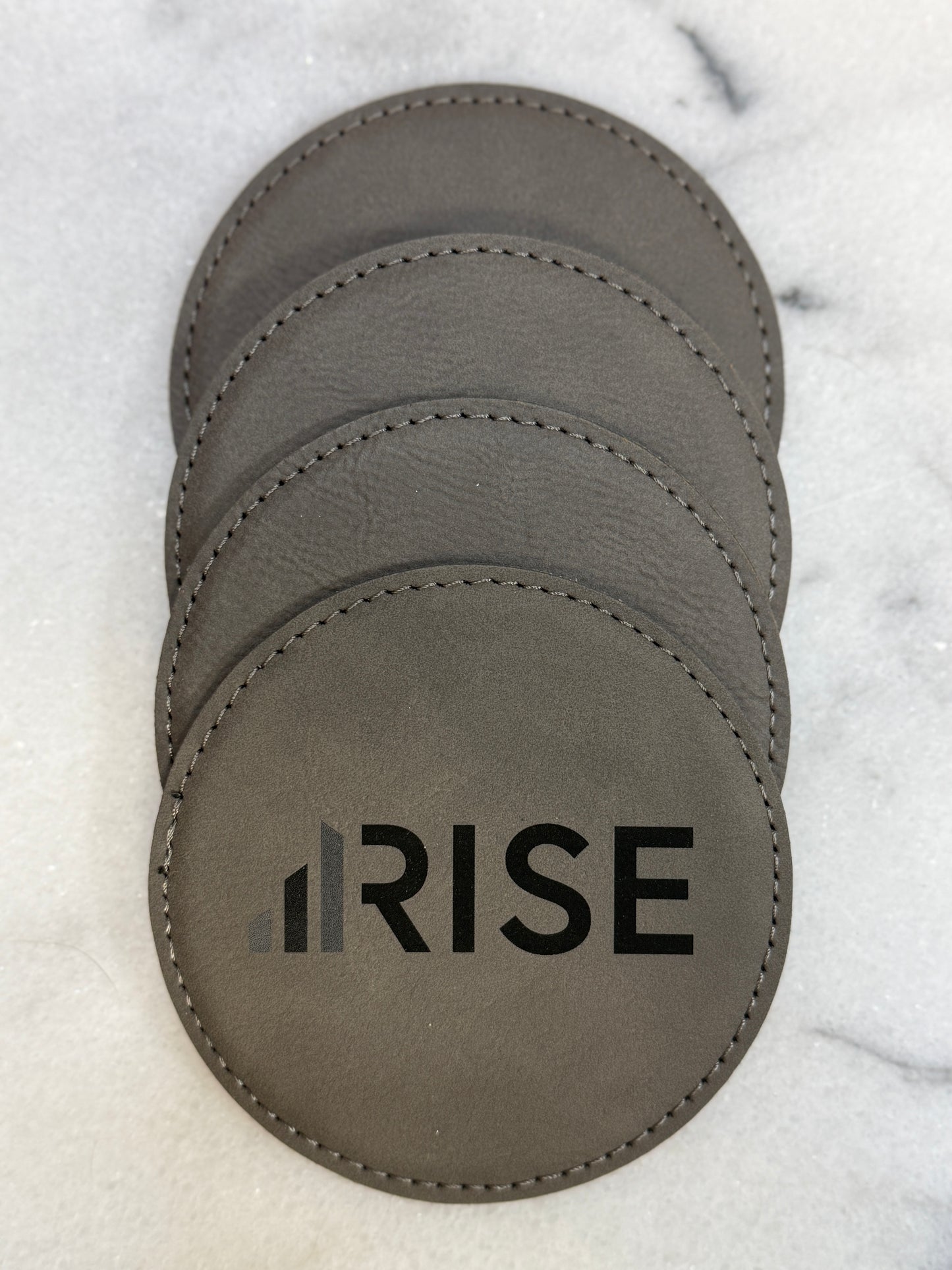 Custom engraved leatherette coasters with company logo for corporate gifting.