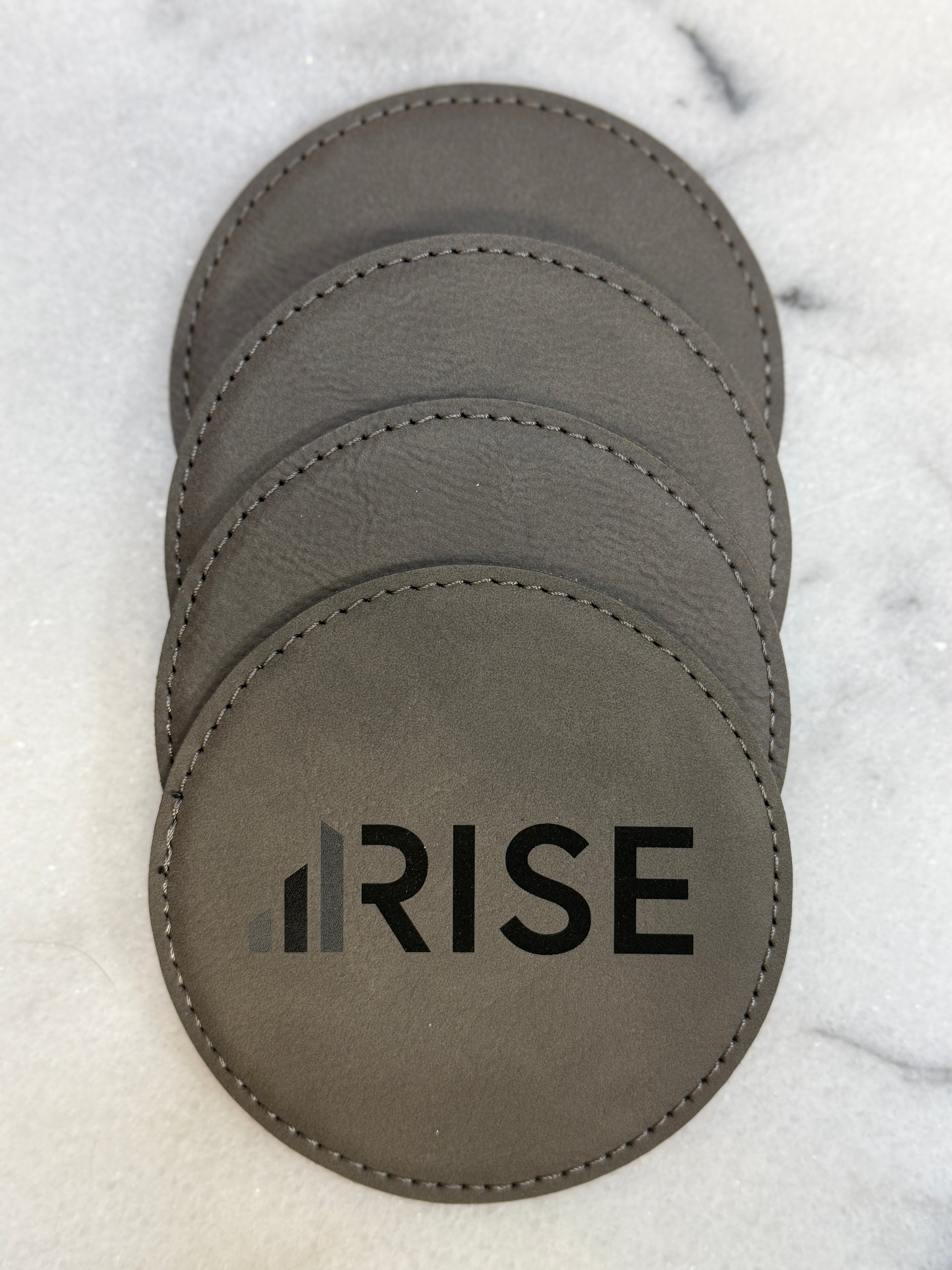 Custom engraved leatherette coasters with company logo for corporate gifting.